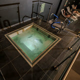Square hot tub with tiled interior on a dark tiled floor