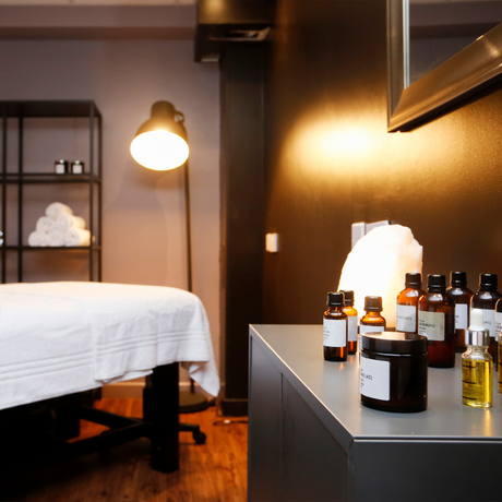 Spa or wellness room with massage table and skincare products on a counter.