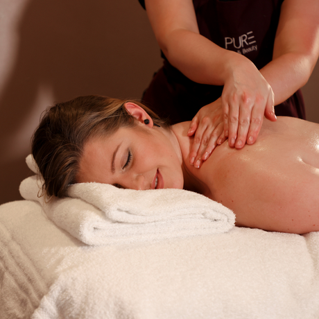 Person receiving a massage with 'PURE' branded clothing in the background